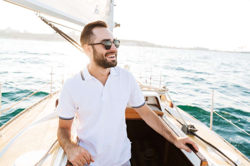 Homme en polo blanc sur un bateau pendant ses vacances d’été