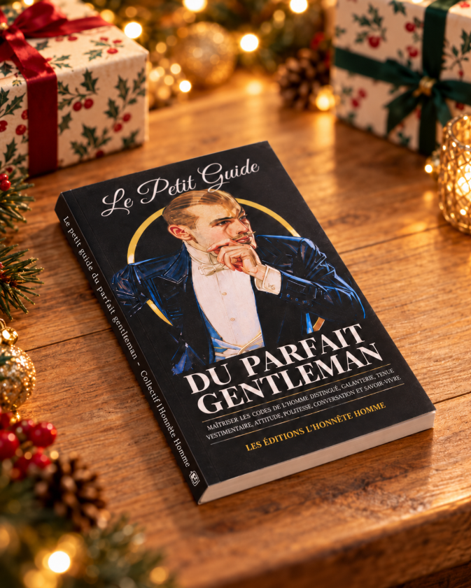 Le Petit Guide du Parfait Gentleman posé à plat sur une table en bois, dans un décor de Noël avec cadeaux et lumières en arrière-plan